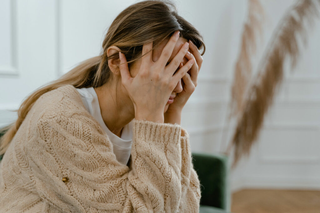 Woman with hands over face in despair.