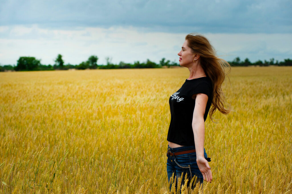 Woman with inspired posture in expansive wheat field.